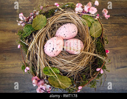Ostern Dekoration, Stroh, Nest mit Eiern und rosa Blüten Stockfoto