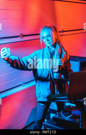 Stilvolle blond dj-Frau mit Flasche und unter selfie in Nachtclub Stockfoto