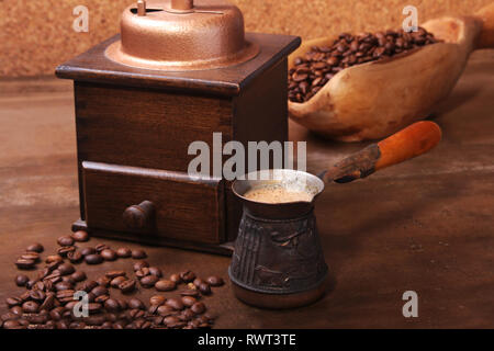Alte hölzerne Schaufel mit Kaffeebohnen, Kaffeemühle und türkischen Kaffee in Cezve auf dunklen Tisch aus Stein. Stockfoto