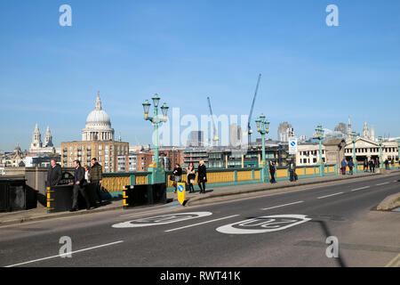 Menschen zu Fuß über die Southwark Bridge an einem sonnigen Tag im Februar mit der St. Pauls Kathedrale und Stadt Krane im Hintergrund London England UK KATHY DEWITT Stockfoto