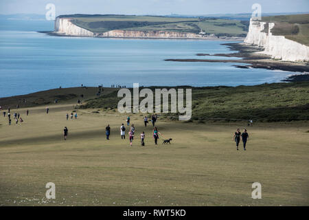 Große Gruppe von gemischter Leute genießen Sie einen Spaziergang entlang der South Downs Way mit dem Severn Schwestern Kreidefelsen im Hintergrund East Sussex England Großbritannien Stockfoto