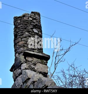 Kreisförmige Trockenmauern Giebelseite Schornstein auf ruiniert Schottischen Croft Haus mit Netzkabel Overhead. Stockfoto