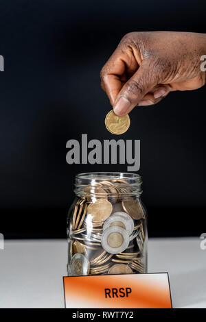 African American nigerianischen Frau Münzen in die Rrsp jar ablegen Stockfoto