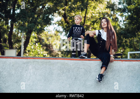 Schöne junge Hipster Mamma und kleinen Sohn Am Skatepark Stockfoto