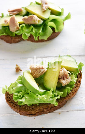 In der Nähe von offenen Thunfisch Sandwiches mit Avocado und Salatblätter auf hellem Holztisch. Lecker Thunfisch Brötchen zum Frühstück. Gesunden Snack. Stockfoto