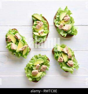 Sandwichs mit Thunfisch, Avocado und Salatblätter öffnen. Lecker Thunfisch Brötchen zum Frühstück. Gesunden Snack. Ansicht von oben, flach Stockfoto