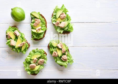 Gesunde Thunfisch Sandwiches mit Avocado und Salatblätter über hellen Hintergrund mit kopieren. Lecker Thunfisch Brötchen zum Frühstück oder einen Snack. Zu Stockfoto