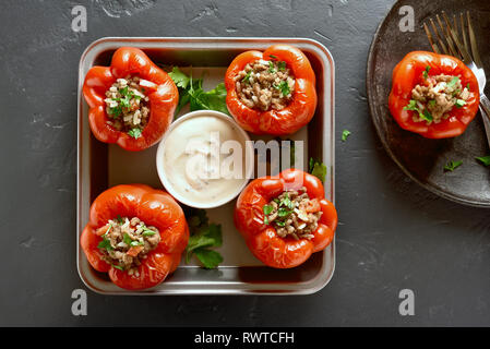 Rote Paprika mit Hackfleisch, Reis, Zwiebel auf schwarzen Stein Hintergrund gefüllt. Ansicht von oben Stockfoto