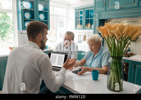 Alte Paar diskutieren mit einem Berater über Ruhestand in den Speisesaal. Geldanlage und Versicherung während der goldenen Jahre. Stockfoto