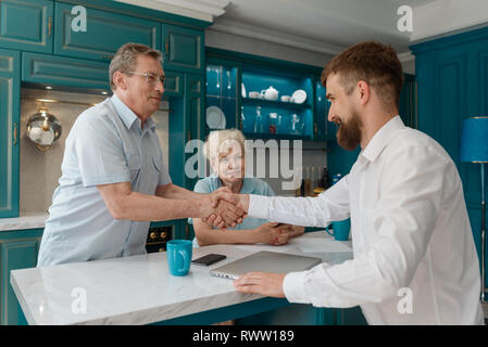 Agent und Client Händeschütteln nach dem erfolgreichen Abschluss eines Abkommens. Ältere Paar verkauft. Immobilien Konzept. Stockfoto