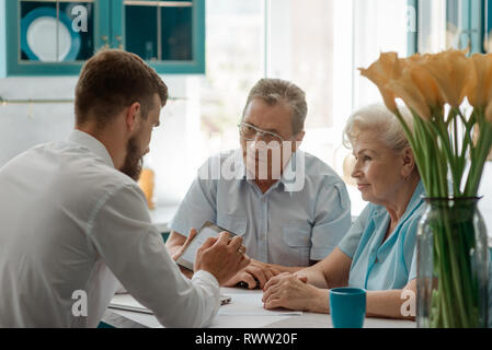 Alte Ehepaar im Gespräch mit einem Finanzberater in ihrer Heimat. Planen eines sicheren und angenehmen Ruhestand. Stockfoto