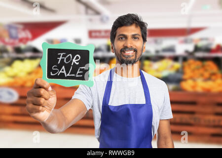 Vertrauenswürdige Supermarkt oder SB-Warenhaus indischen männlichen Mitarbeiter Tafel mit Kreide Text zum Verkauf Stockfoto