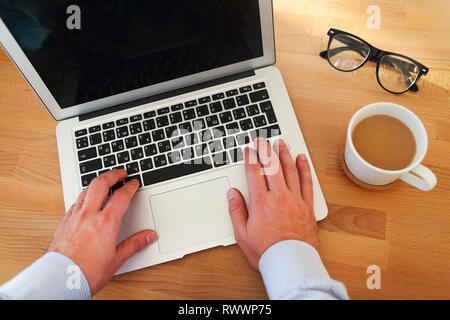 Blick von oben auf die Menschen Arbeiten am Laptop und in Tasse Kaffee während sitzt an seinem Arbeitsplatz Stockfoto