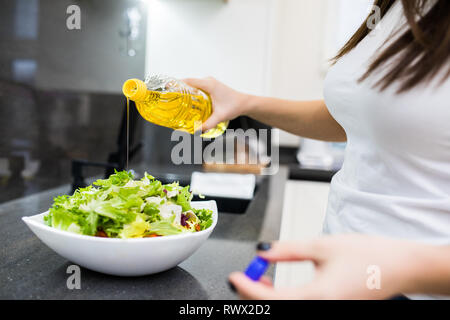 Nahaufnahme der jungen Frau dressing Salat mit Olivenöl zu Hause Stockfoto