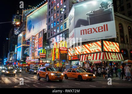 Helles Neon signage blinkt über Massen und taxi Datenverkehr, der an den Times Square der Veranstaltungsort der berühmten New. Mac Mc Donald's Times Square Ne Stockfoto