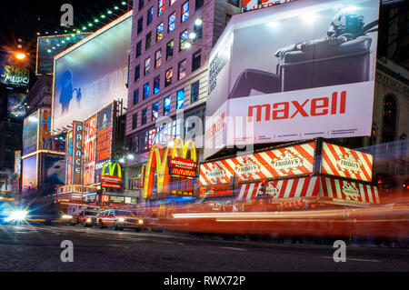 Helles Neon signage blinkt über Massen und taxi Datenverkehr, der an den Times Square der Veranstaltungsort der berühmten New. Mac Mc Donald's Times Square Ne Stockfoto