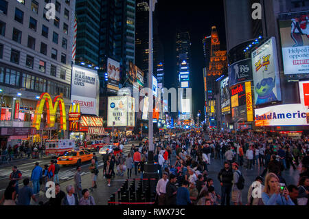 Helles Neon signage blinkt über Massen und taxi Datenverkehr, der an den Times Square der Veranstaltungsort der berühmten New. Mac Mc Donald's Times Square Ne Stockfoto