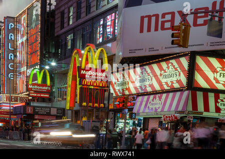 Helles Neon signage blinkt über Massen und taxi Datenverkehr, der an den Times Square der Veranstaltungsort der berühmten New. Mac Mc Donald's Times Square Ne Stockfoto