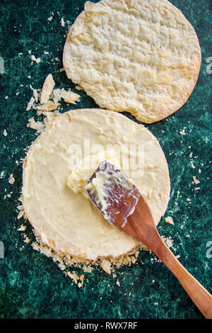 Runde 2-in-1-napoleon Kuchen mit Pudding und streute Krumen auf grünem Marmor Tabelle, Ansicht von oben. Der Prozess des Kochens, Rezept Desserts. Stockfoto