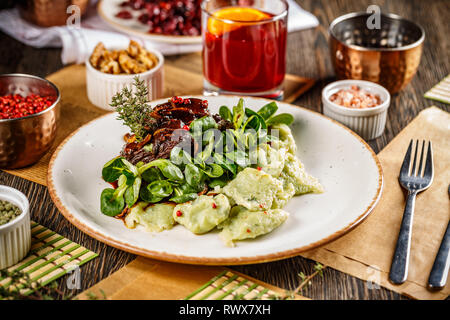 Rindfleisch Wangen in Soße mit Gnocchi und Baby Spinat serviert auf einem weißen Teller Stockfoto