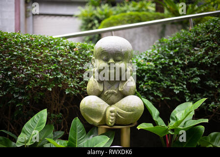 Fo Guang Shan-größten buddhistischen Kloster in Taiwan - ein süßes, kleines Stein stille Buddha Statue in einer Pose, die seine Ohren. Kaohsiung, Nov 2018 Stockfoto