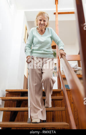 Ältere Frau zu Hause mit einem Spazierstock die Treppe nach unten zu bekommen Stockfoto