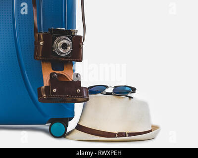 Stilvolle, blaue Koffer, modischer Sonnenhut, vintage Kamera in einem braunen Lederetui. Weiß, isolierte Hintergrund. Close-up. Von der Seite. Vorbereitung für Th Stockfoto