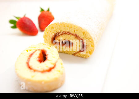 Swiss roll mit Erdbeermarmelade auf einem weißen Tisch Stockfoto