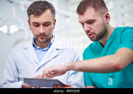 Zwei kaukasischen männliche Zahnärzte x-Analyse ray in der zahnmedizinischen Kabinett. Nahaufnahme Stockfoto