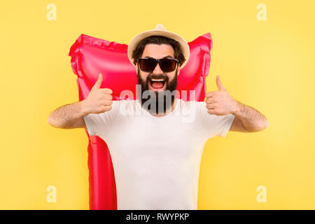 Studio Portrait eines bärtigen Mann in Sonnenbrille und Panama Hut, den Kerl mag zeigt, stehend auf dem Hintergrund einer rosa Aufblasbare swimming Matratze Stockfoto