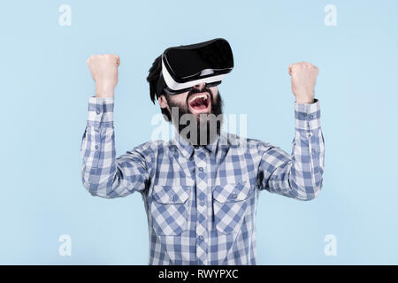 Bärtiger Mann freut sich über Sieg in Gläser der Virtuellen Realität (VR-Brille) Stockfoto