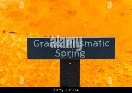 Schild Grand Prismatic Spring vor Gelb mineralische Ablagerungen, Midway Geyser Basin, Yellowstone National Park, Wyoming, USA Stockfoto