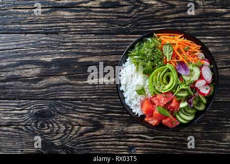 Ansicht von oben der hawaiischen Stil Lachs poke Schüssel mit Reis, Seetang, Avocado Rose, Rettich, Karotten, Gurken und frischen grünen Salat, horizontale Ansicht fr Stockfoto