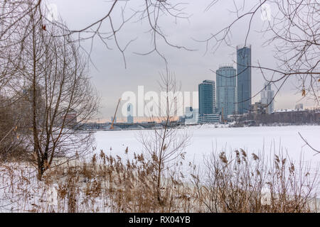 Modernes hohes Gebäude am Ufer des zugefrorenen Teich im Winter Stockfoto