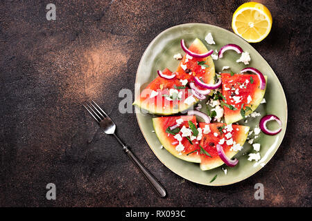 Frische Sommer gegrillter Wassermelone mit Feta Käse, Minze, Zwiebeln auf braunem Hintergrund Stockfoto