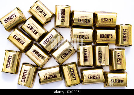 Ein Haufen von Hershey's Milchschokolade mit Mandeln Nuggets im Einzelnen goldfarbenem Wrapper isoliert auf Weiss. Stockfoto