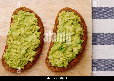 Guacamole Sandwich auf hellen Hintergrund avocado Sandwiches auf Holzbrett und textile Draufsicht Stockfoto