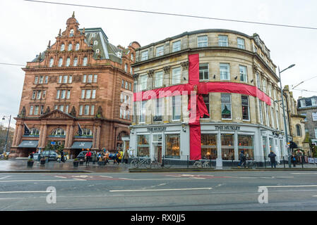 Das Huxley, eine stilvolle Hotelbar im Zentrum von Edinburgh, Schottland, ist zu Weihnachten in ein rotes Band gehüllt. Dahinter das Waldorf Astoria Caledonian. Stockfoto