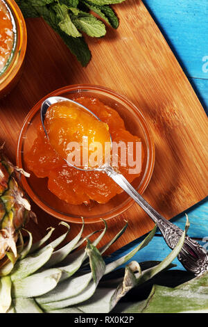 Ananas Marmelade mit frischer Ananas und Minze. Marmelade auf Löffel und jar auf blauem Hintergrund Stockfoto