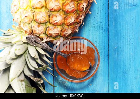 Ananas Marmelade mit frischer Ananas und Minze. Marmelade auf Löffel und jar auf blauem Hintergrund Stockfoto