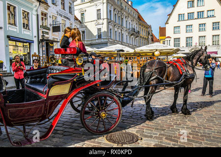 Eine Pferdekutsche und Reiter für die Fahrt in die Stadt an einem langen Sommertag mit Touristen, die mittelalterlichen Gassen, Bars und Cafes Stockfoto