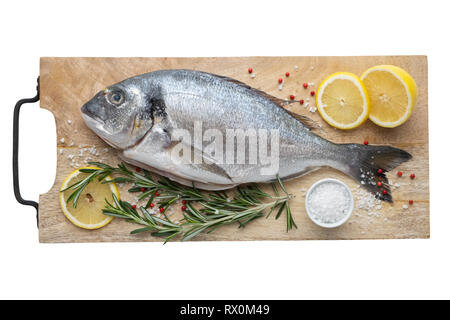 Frische dorado Fisch mit Zitronenscheiben, Salz und Rosmarin auf Schneidebrett. Ansicht von oben, isoliert auf Weiss. Stockfoto