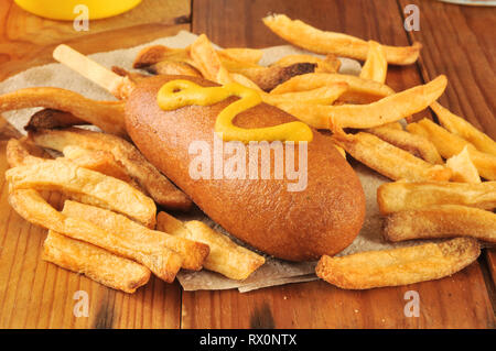 Ein mais Hund mit Senf und Pommes frites auf eine Serviette Stockfoto