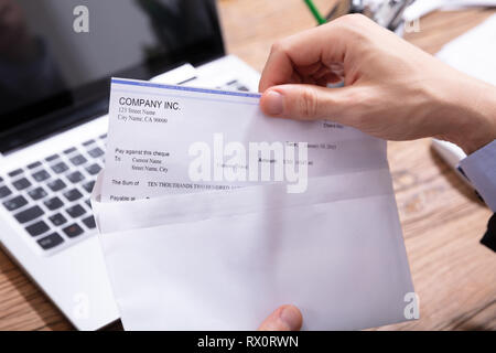 Nahaufnahme der Kaufmann Hand öffnen Umschlag mit Gehaltsscheck über Holz- Schreibtisch Stockfoto