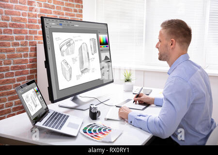 Seitenansicht des Designer Zeichnung Koffer auf Computer mit Grafik Tablett im Büro Stockfoto