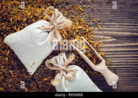 Hintergrund der trockenen Ringelblume Heilpflanzen, zwei Beutel Beutel der aromatischen Gesunde calendula Kräuter und hölzerne Schaufel. Ansicht von oben. Stockfoto