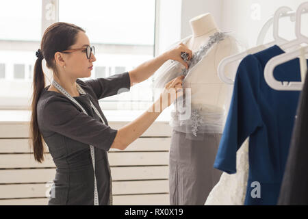 Schneiderin, Schneider, Mode und Showroom Konzept - Seitenansicht der weiblichen Mode Designer Materialien messen auf schaufensterpuppe im Büro Stockfoto