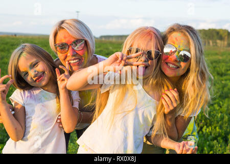 Festival der Holi, Freundschaft, Glück und Urlaub Konzept - fröhlich und lustig Mädchen in Farbe im grünen Feld abgedeckt Stockfoto