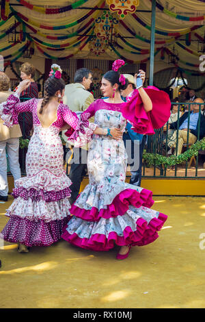 Junge Frauen mit Flamenco Kleider und Tanzendes evillanas' an der Feria de Abril in Sevilla Messe (Feria de Sevilla). Stockfoto