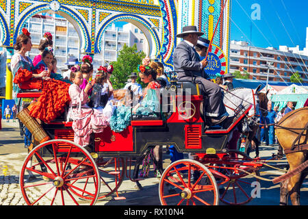 Spanische Familien in traditionellen und farbenfrohen Kleid in einem Pferd reisen Kutschen im April Messe. Stockfoto